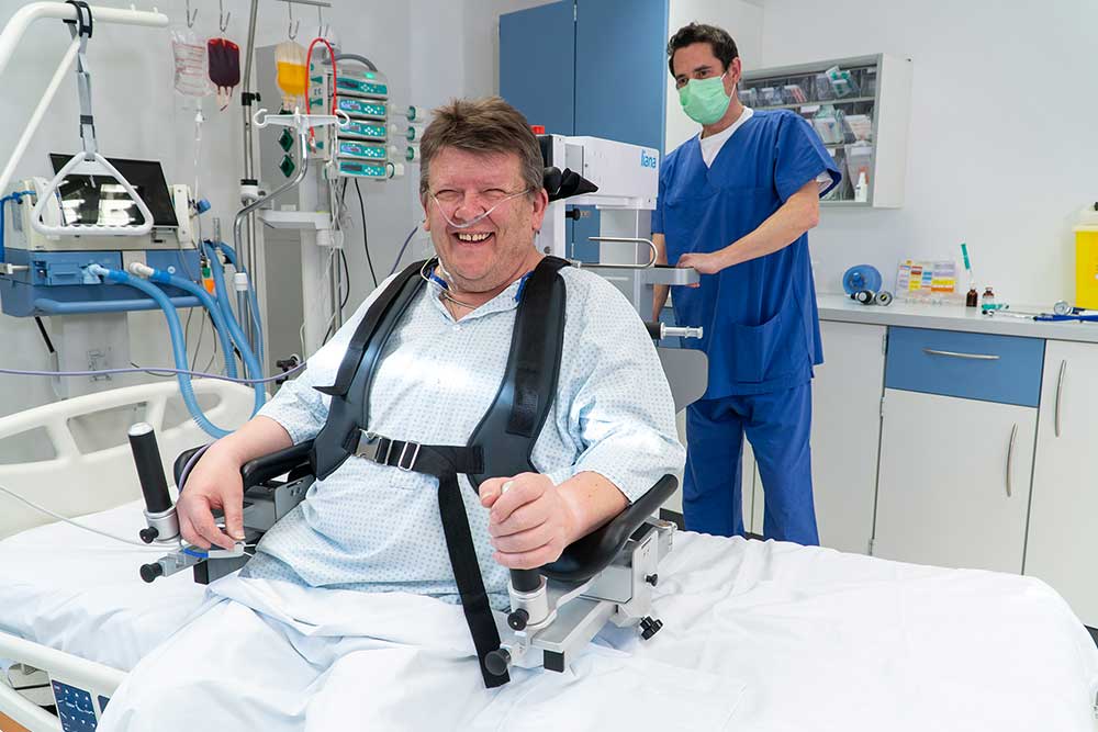 Lächelnder Patient auf Liana mit Pflegr im Hintergrund