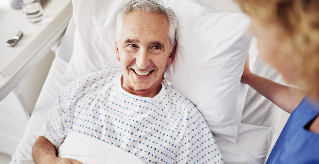 Älterer Patient lächelt seine Pflegerin an